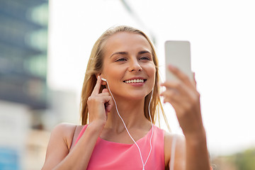 Image showing happy young woman with smartphone and earphones