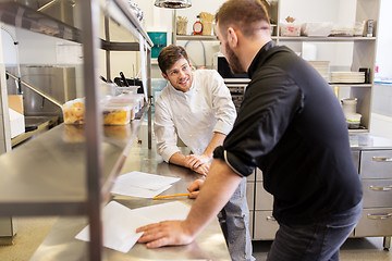 Image showing chef and cook with grocery list at kitchen