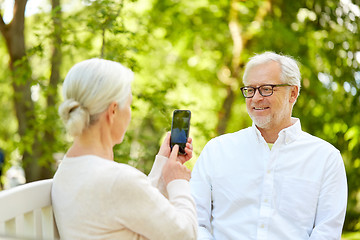 Image showing old woman photographing man by smartphone in park