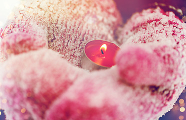 Image showing close up of hands in winter mittens holding candle