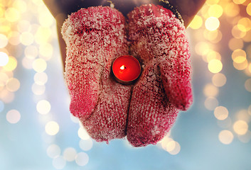 Image showing close up of hands in winter mittens holding candle