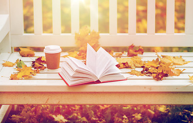 Image showing open book and coffee cup on bench in autumn park