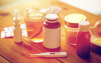 Image showing drugs, thermometer, honey and cup of tea on wood