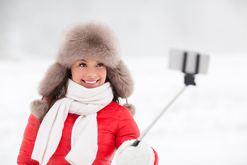 Image showing happy woman with selfie stick outdoors in winter