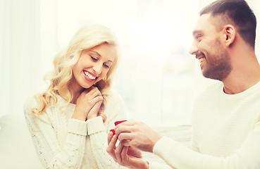 Image showing happy man giving engagement ring to woman at home