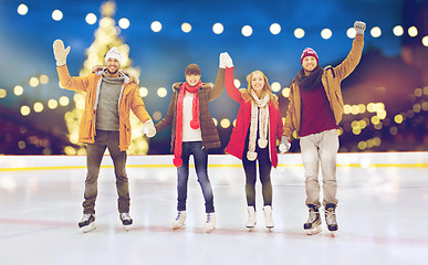 Image showing happy friends waving hands on outdoor skating rink