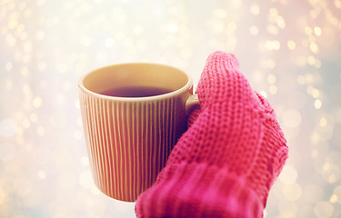 Image showing close up of hand in winter mitten holding tea mug