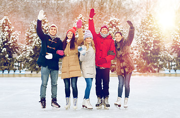 Image showing happy friends ice skating on rink outdoors