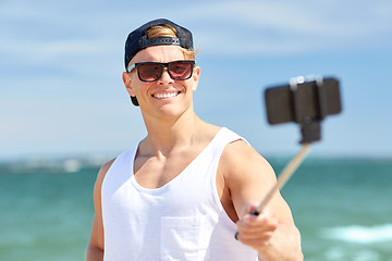 Image showing man with smartphone selfie stick on summer beach