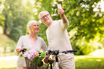 Image showing senior couple with bicycles taking selfie at park