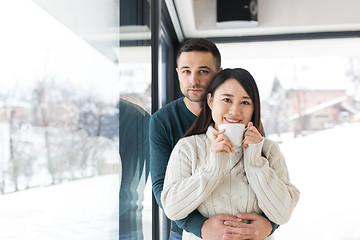 Image showing multiethnic couple enjoying morning coffee by the window