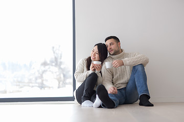 Image showing multiethnic couple enjoying morning coffee by the window