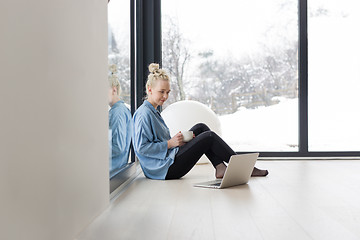 Image showing woman drinking coffee and using laptop at home