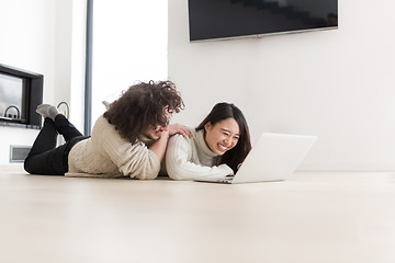 Image showing young multiethnic couple using a laptop on the floor