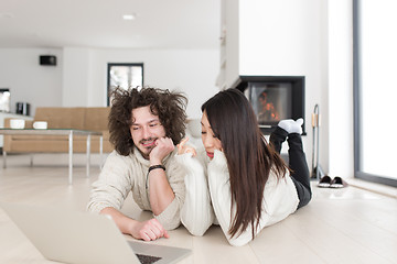 Image showing young multiethnic couple using a laptop on the floor