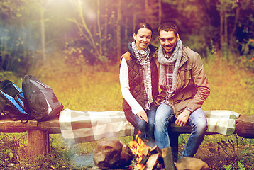 Image showing happy couple sitting on bench near camp fire