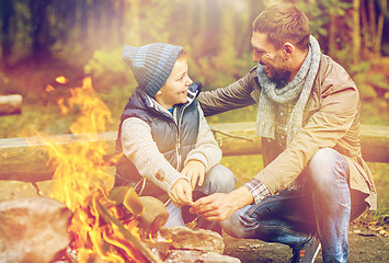 Image showing father and son roasting marshmallow over campfire