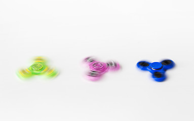 Image showing three spinning fidget spinners on white background