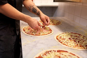 Image showing cook hands adding champignons to pizza at pizzeria