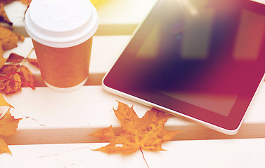 Image showing tablet pc and coffee cup on bench in autumn park