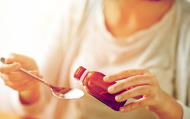 Image showing woman pouring medicine from bottle to spoon