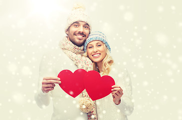 Image showing smiling couple in winter clothes with red hearts