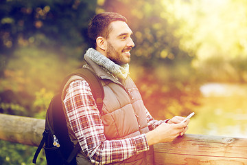 Image showing happy man with backpack and smartphone outdoors