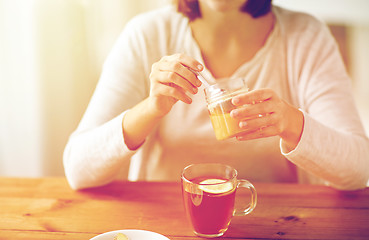 Image showing close up of ill woman drinking tea with honey