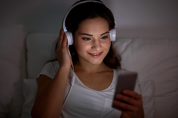 Image showing woman with smartphone and headphones in bed