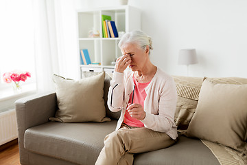 Image showing senior woman with glasses having headache at home