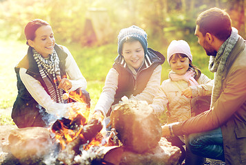 Image showing happy family roasting marshmallow over campfire