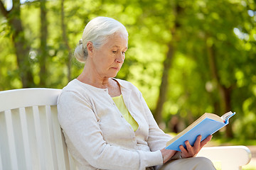 Image showing happy senior woman reading book at summer park