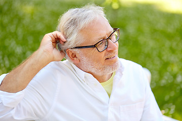 Image showing happy senior man in glasses sitting at summer park