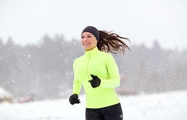 Image showing happy woman running along snow covered winter road