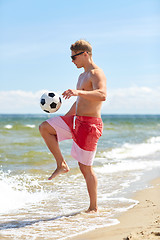 Image showing young man with ball playing soccer on beach