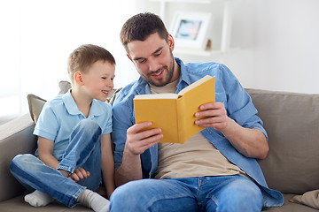 Image showing happy father and son reading book sofa at home