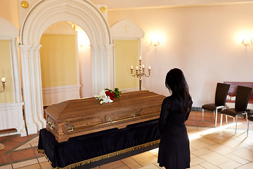 Image showing sad woman with coffin at funeral in church