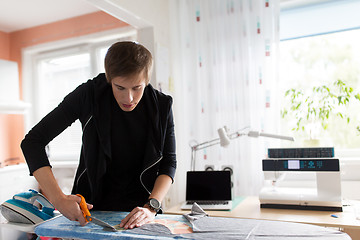 Image showing fashion designer cutting fabric at studio