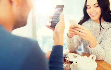 Image showing happy couple with smartphones drinking tea at cafe