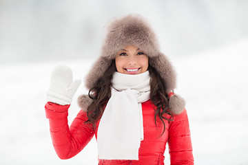 Image showing happy woman in winter fur hat waving hand outdoors