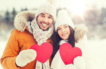 Image showing happy couple with red hearts over winter landscape