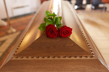 Image showing red rose flowers on wooden coffin in church