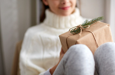 Image showing girl with christmas gift sitting on sill at home