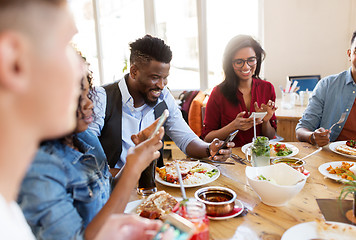 Image showing happy friends with smartphones at restaurant