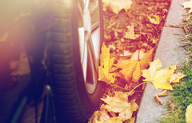 Image showing close up of car wheel and autumn leaves