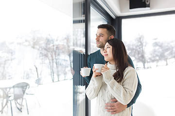Image showing multiethnic couple enjoying morning coffee by the window