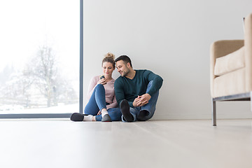 Image showing young couple sitting on the floor near window at home