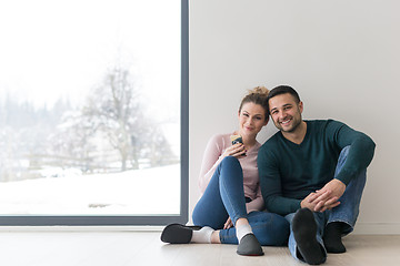 Image showing young couple sitting on the floor near window at home