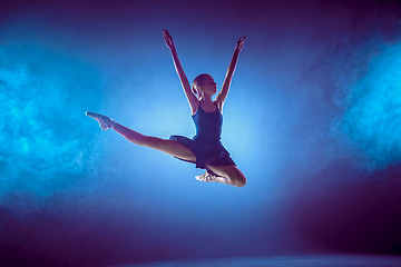 Image showing Beautiful young ballet dancer jumping on a lilac background.