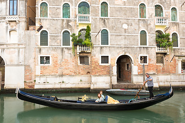 Image showing Venetian gondolier punting gondola through green canal waters of Venice, Italy